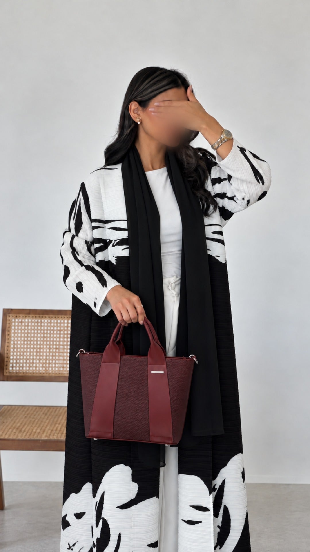Reem Top-Handle Bag in wine, carried with a black and white Panda abaya